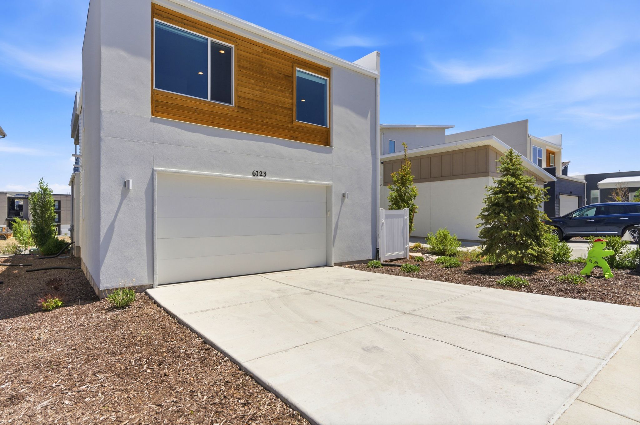 Modern stucco exterior with wood-finish siding accents, a two-car garage, and a concrete driveway