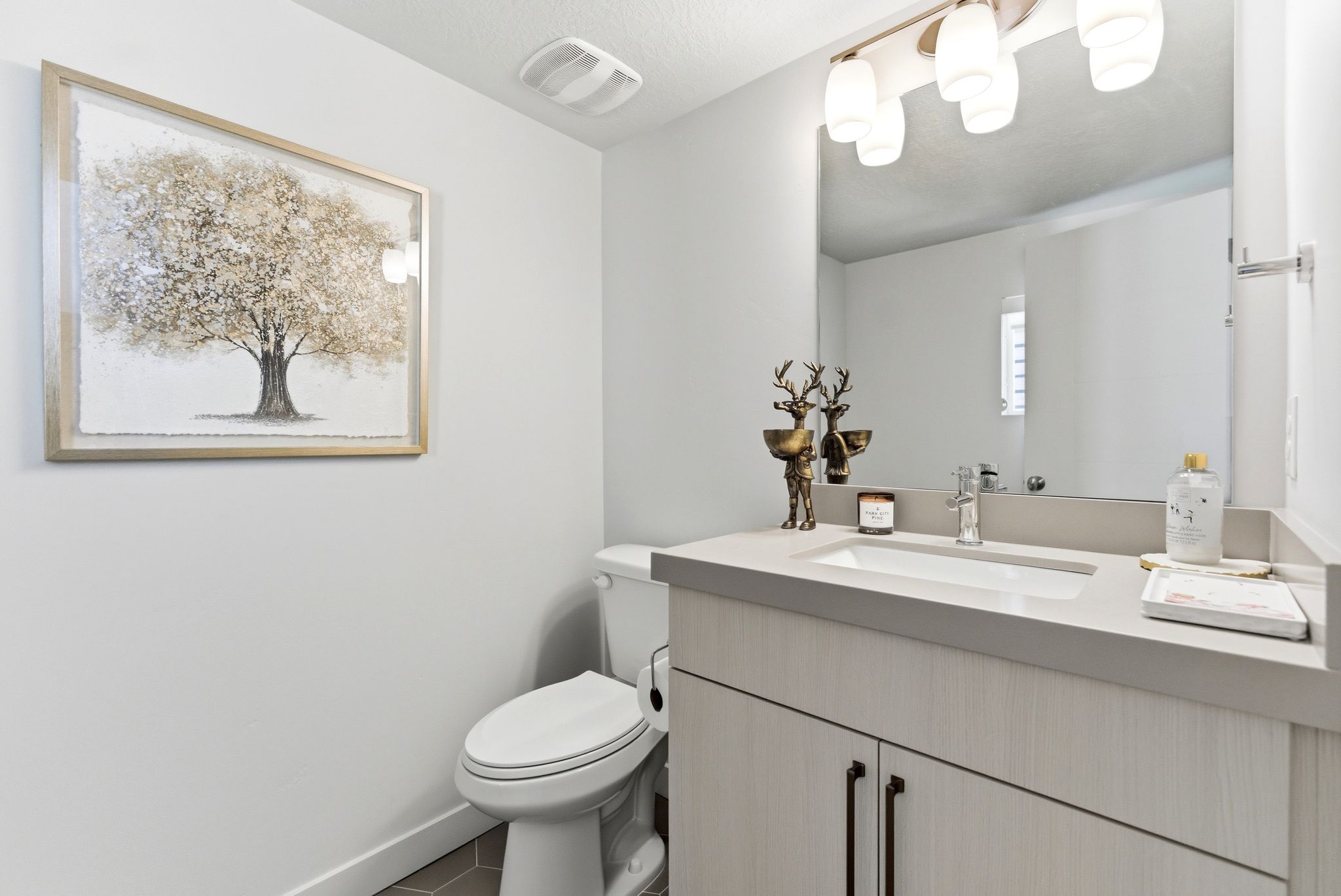 Bathroom featuring a light wood-finish vanity with a single basin sink, a gray countertop, and an overhead vanity light fixture