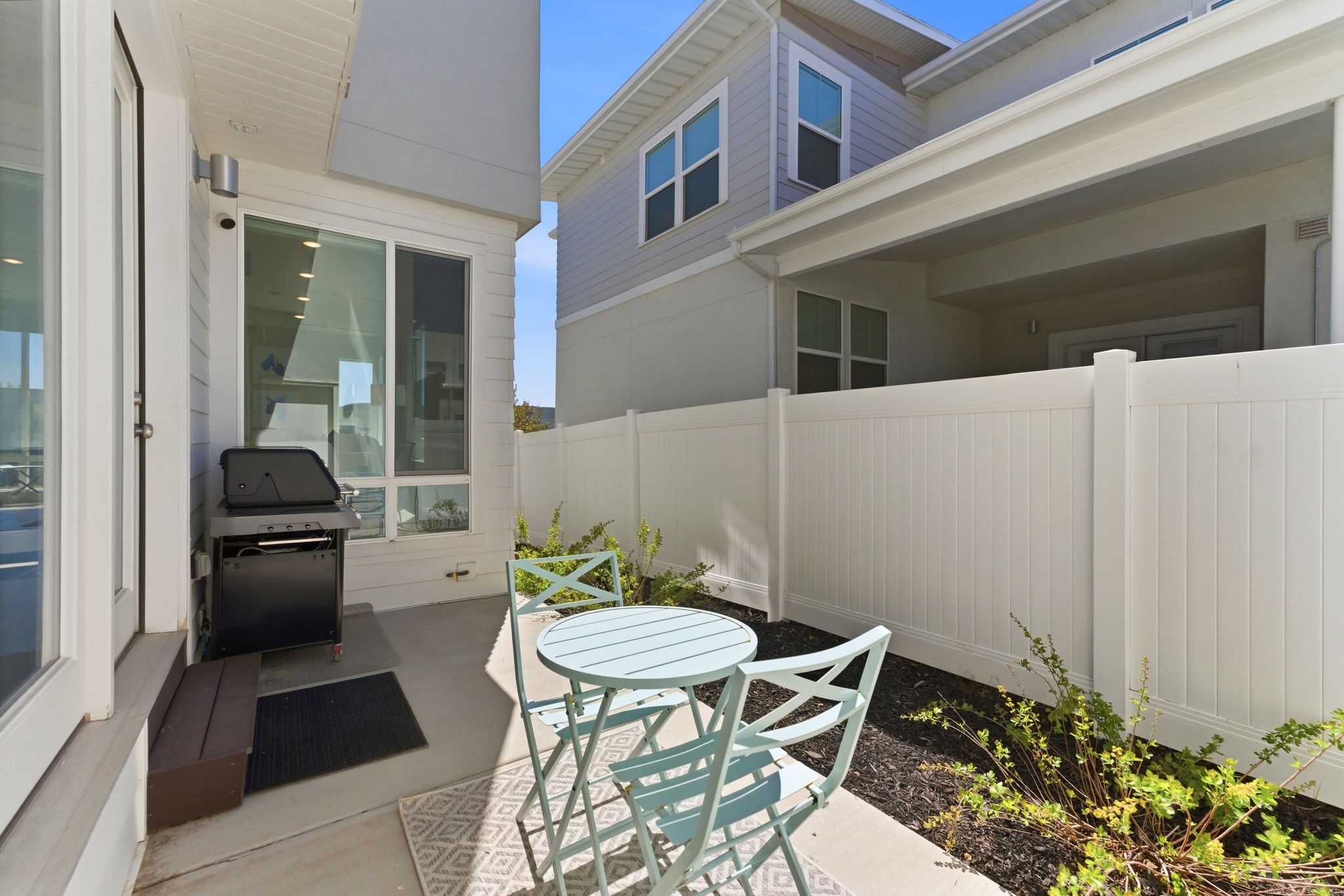 Private patio featuring concrete flooring and a white privacy fence
