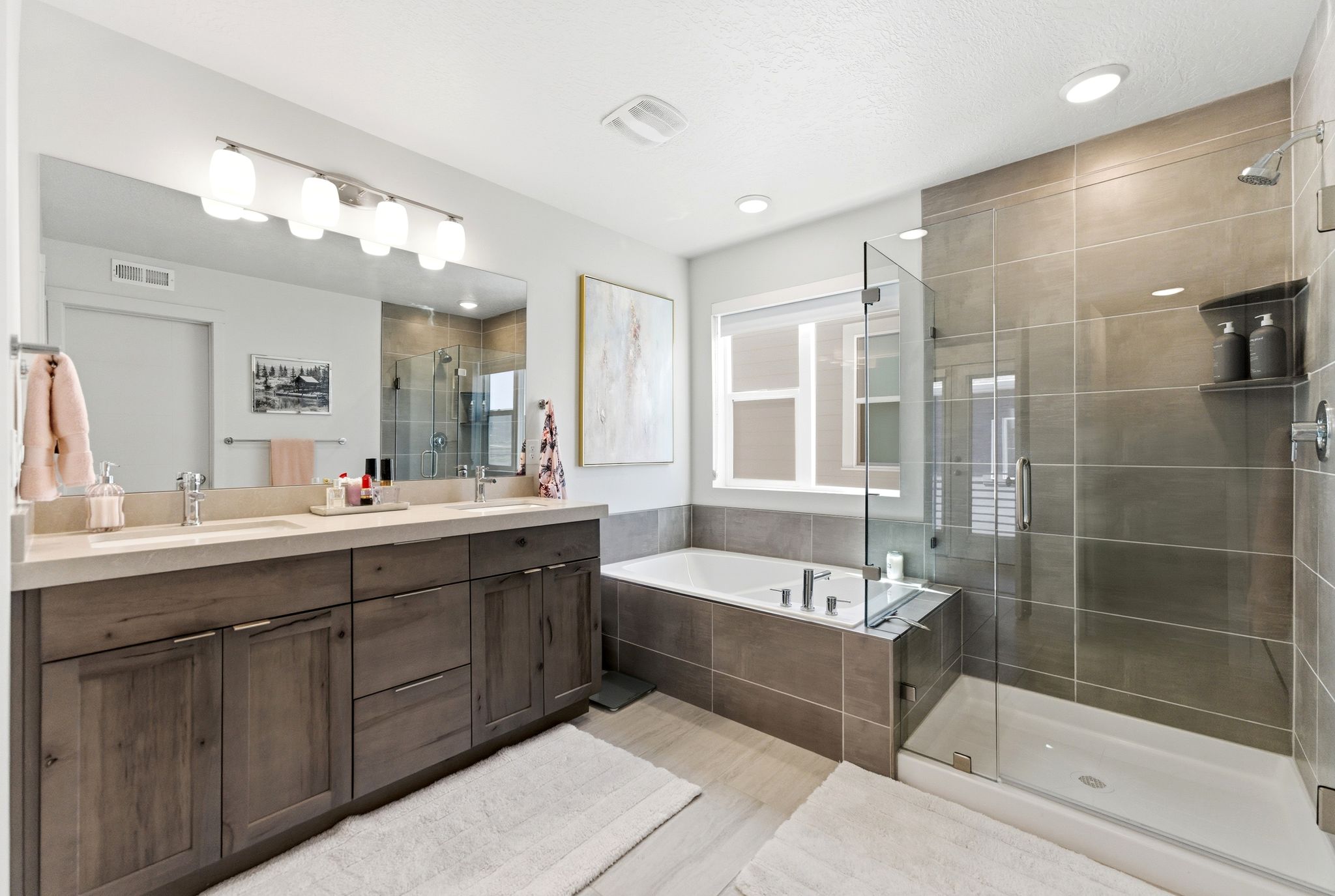 Contemporary bathroom featuring a spacious walk-in shower with glass enclosure, separate soaking tub, dual vanity with undermount sinks, and a large mirror with integrated lighting