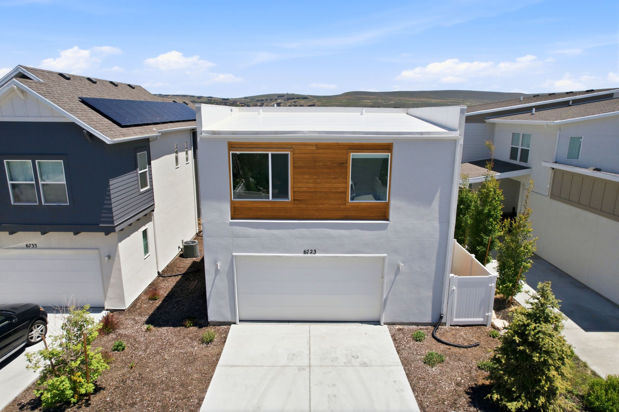 Contemporary façade featuring a white stucco exterior, wood-panel accent, and a flat roofline