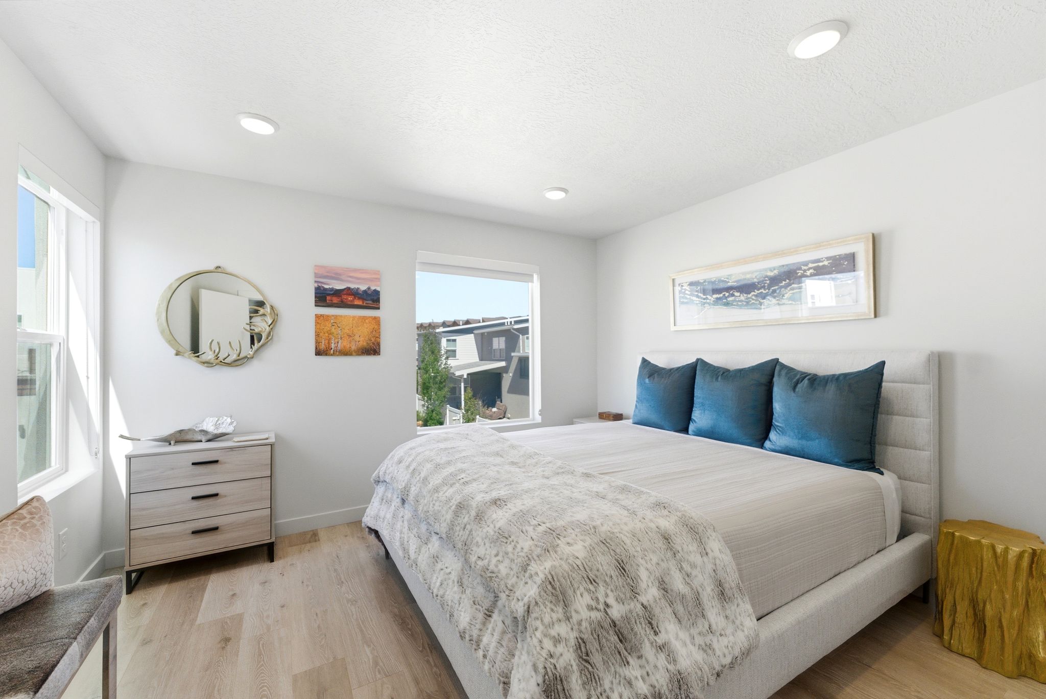 Well-lit bedroom featuring light wood-finish flooring, recessed ceiling lights, and multiple windows