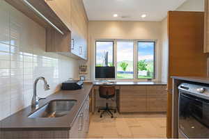Dedicated work-from-home area featuring expansive windows, integrated cabinetry, a built-in countertop, and a stainless steel sink with a gooseneck faucet