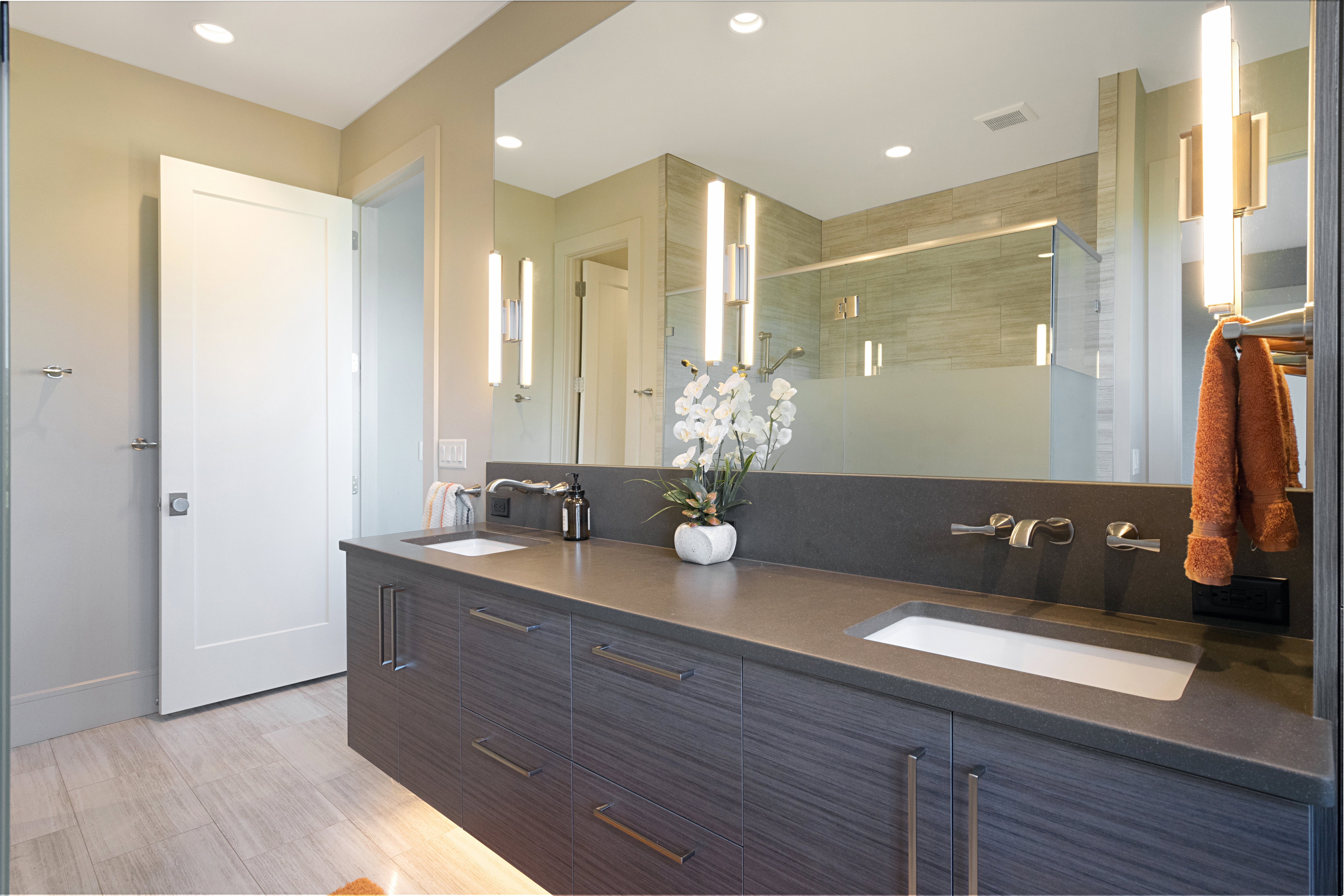 Floating vanity with integrated dual sinks and a dark countertop, complemented by modern wall-mounted faucets