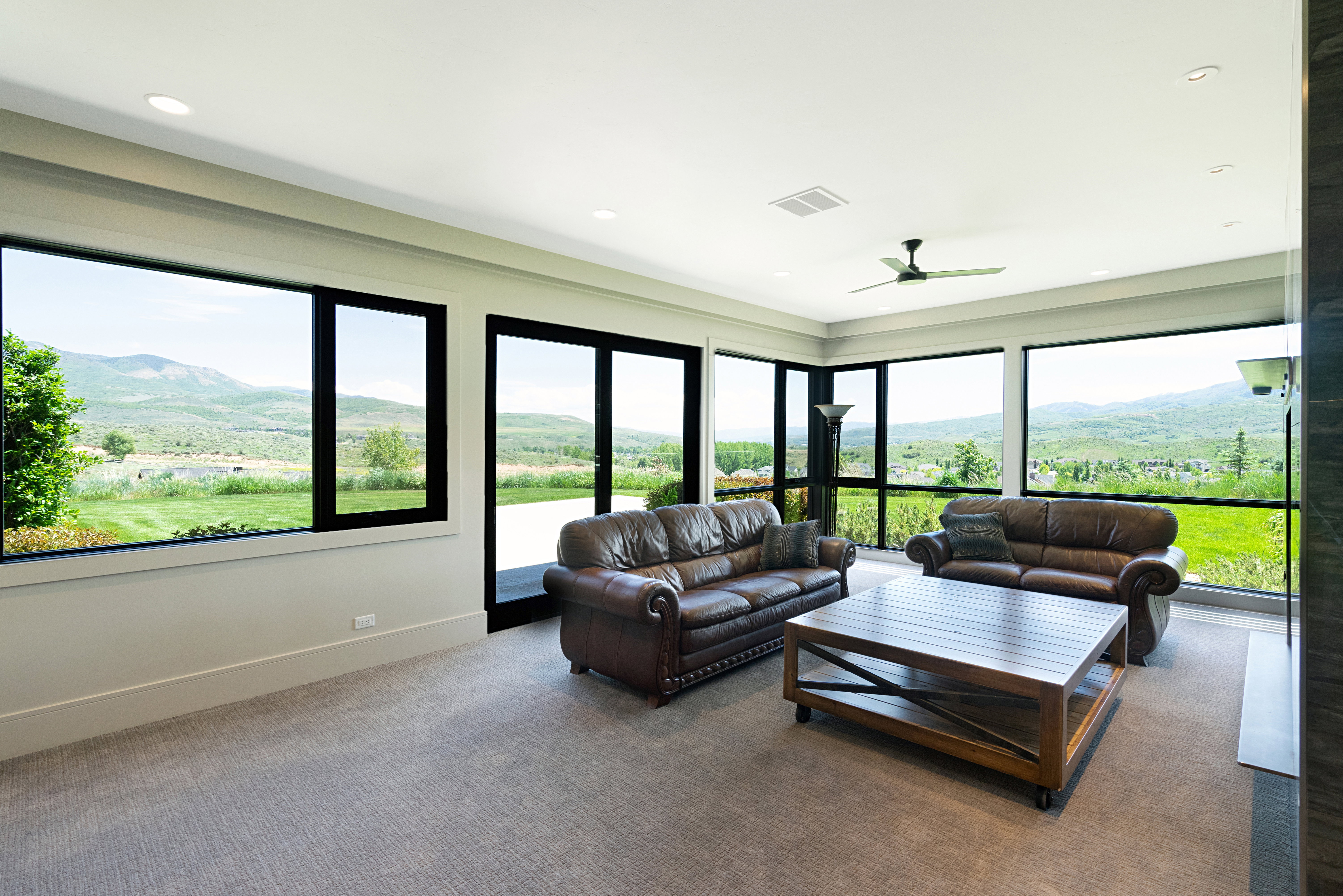 Spacious room featuring extensive window walls, recessed lighting, a ceiling fan, and carpeted flooring