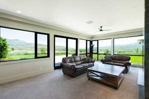 Spacious room featuring extensive window walls, recessed lighting, a ceiling fan, and carpeted flooring