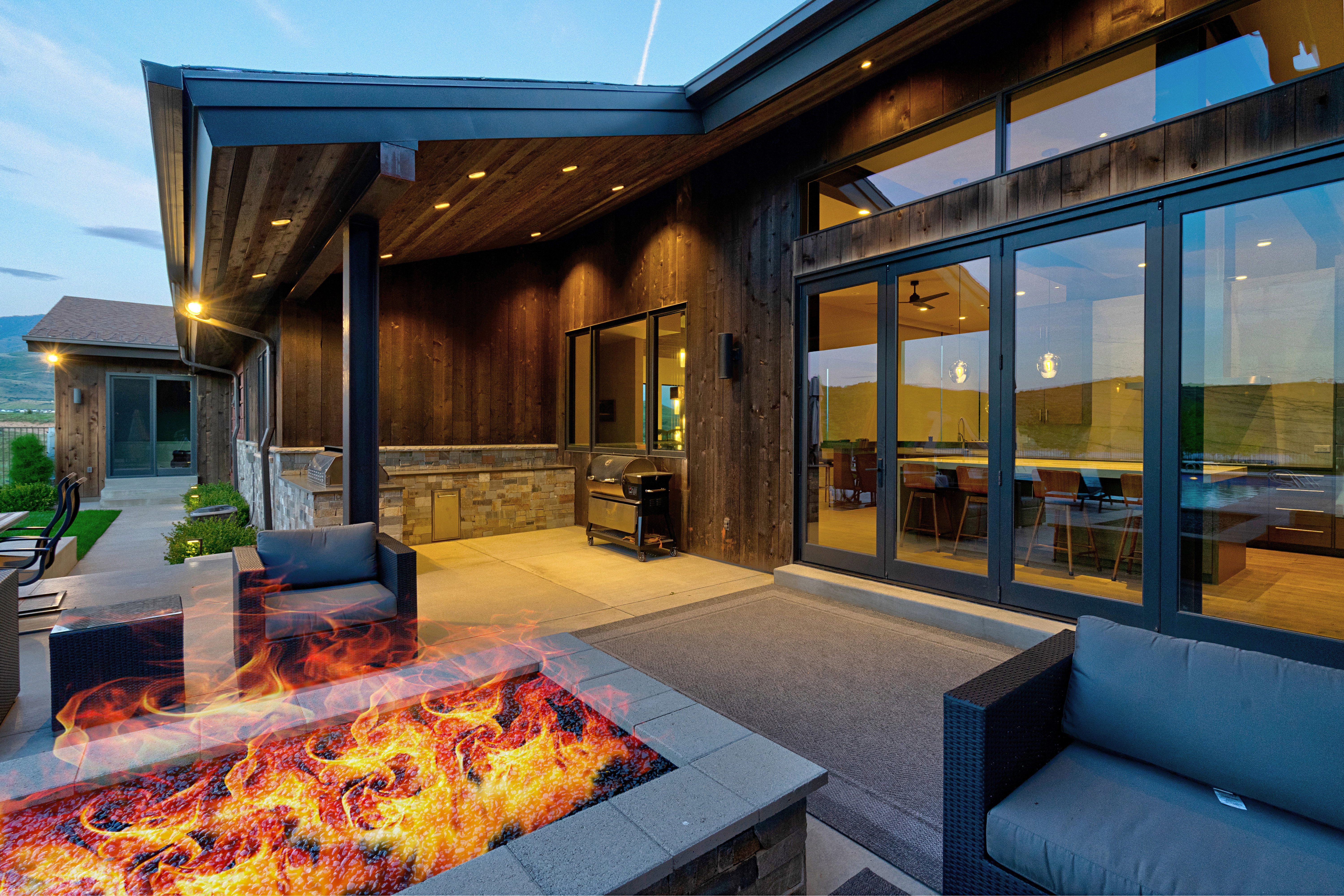Outdoor patio featuring a built-in fire pit, stone accent wall, and expansive multi-panel glass doors
