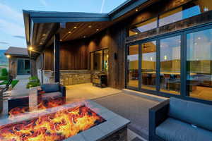 Outdoor patio featuring a built-in fire pit, stone accent wall, and expansive multi-panel glass doors