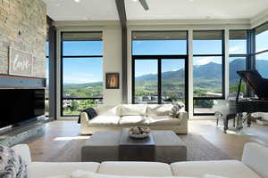 Contemporary living area featuring expansive floor-to-ceiling windows, light wood-finish flooring, and a floor-to-ceiling stone-clad fireplace