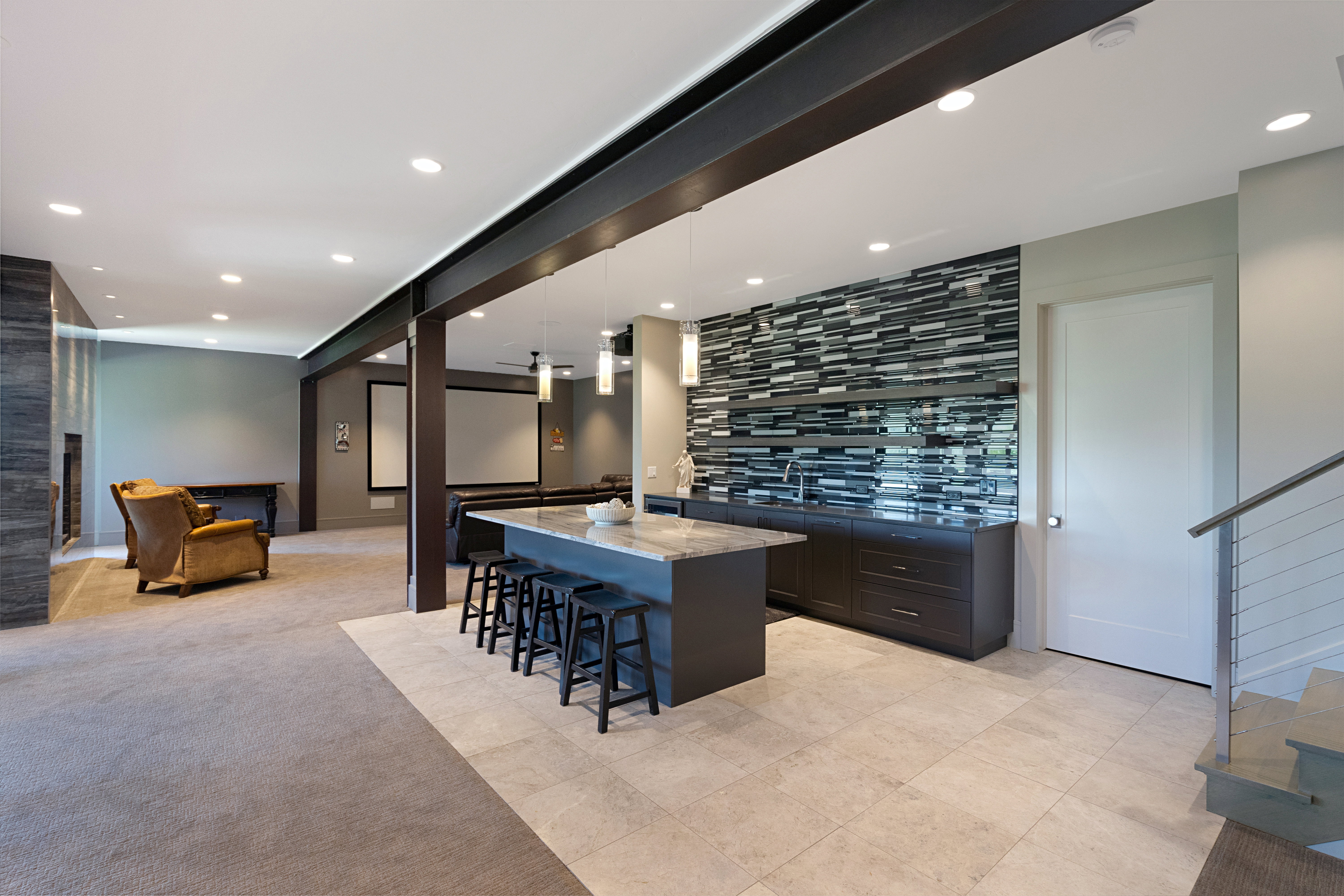 Entertainment space featuring a wet bar with a tiled backsplash, an island with seating, recessed lighting, and a projection screen area