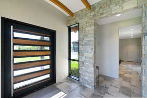 Modern entry featuring a dark-framed door with horizontal wood and glass inserts, a full-height sidelight, and a stacked stone wall accent