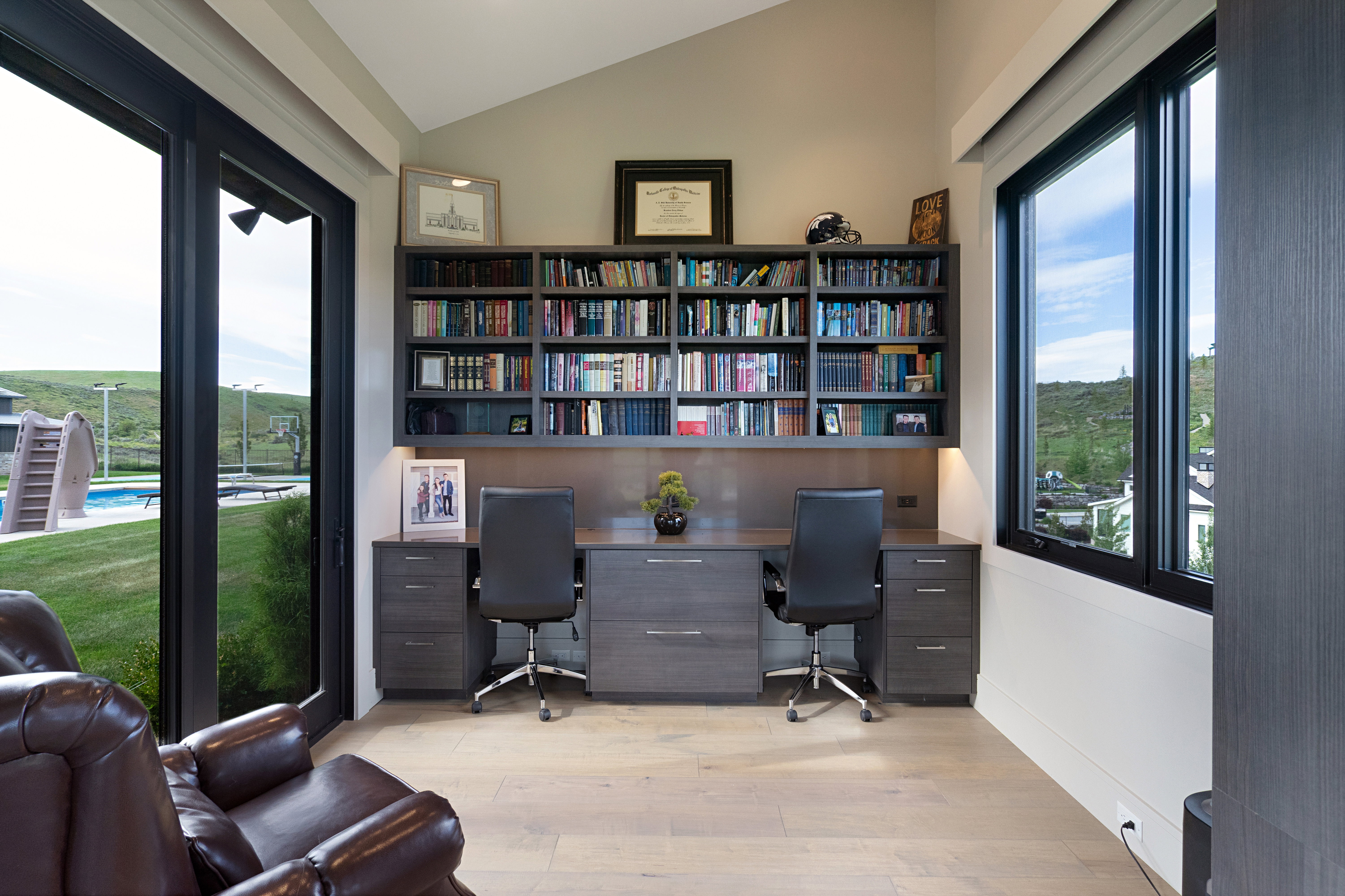 Dedicated office space featuring built-in shelving, two workstations, and ample natural light
