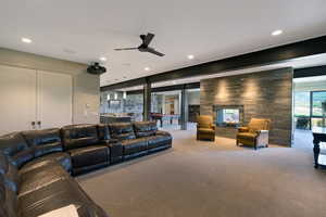 Spacious entertainment area featuring a modern fireplace with a stone surround, integrated ceiling lighting, a ceiling fan, and large glass patio doors