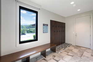 Entryway featuring a built-in wood bench, a coat rack with pebble detailing, and large format tile flooring