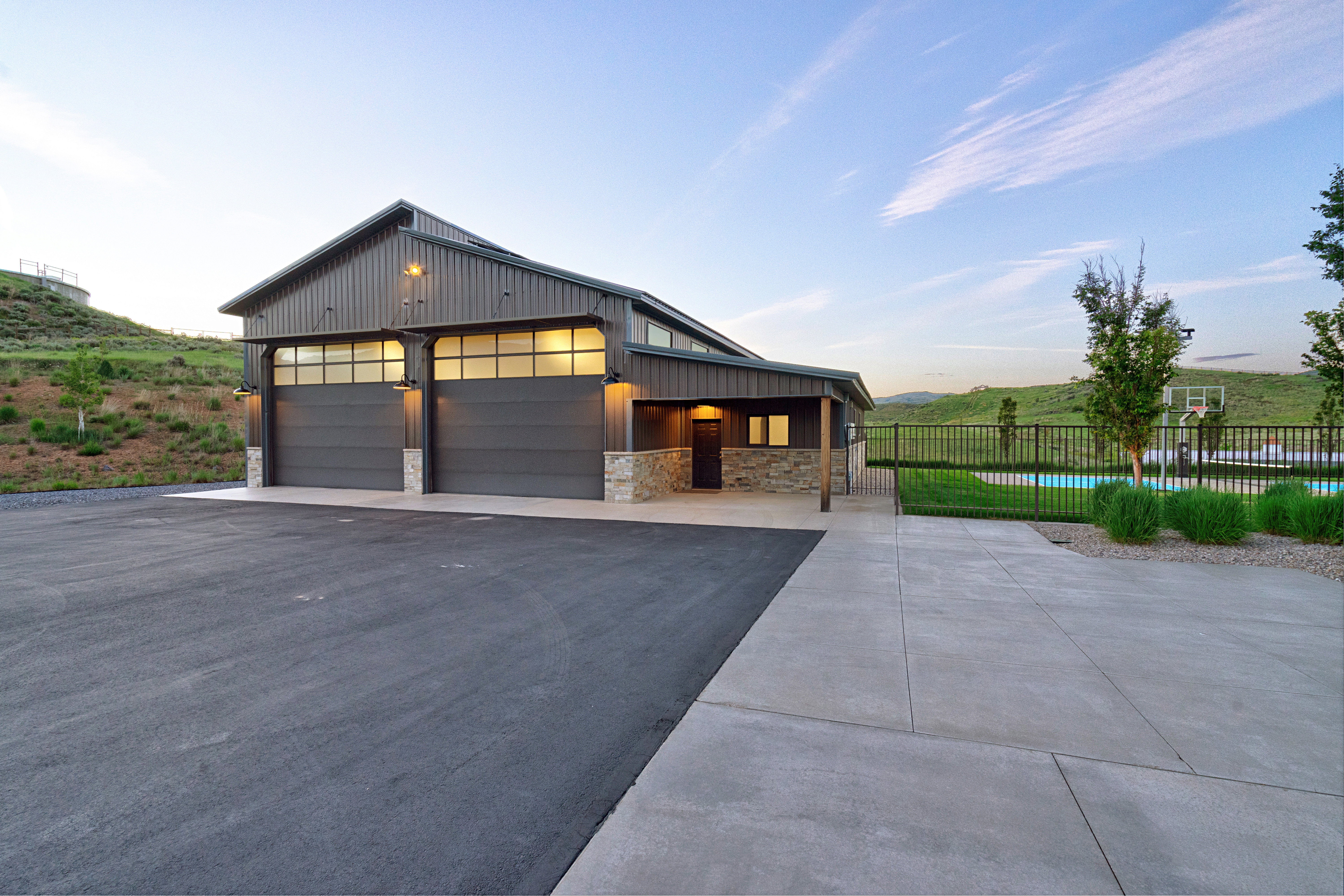 Modern barn-style structure with two overhead garage doors featuring transom windows, complemented by stone accents