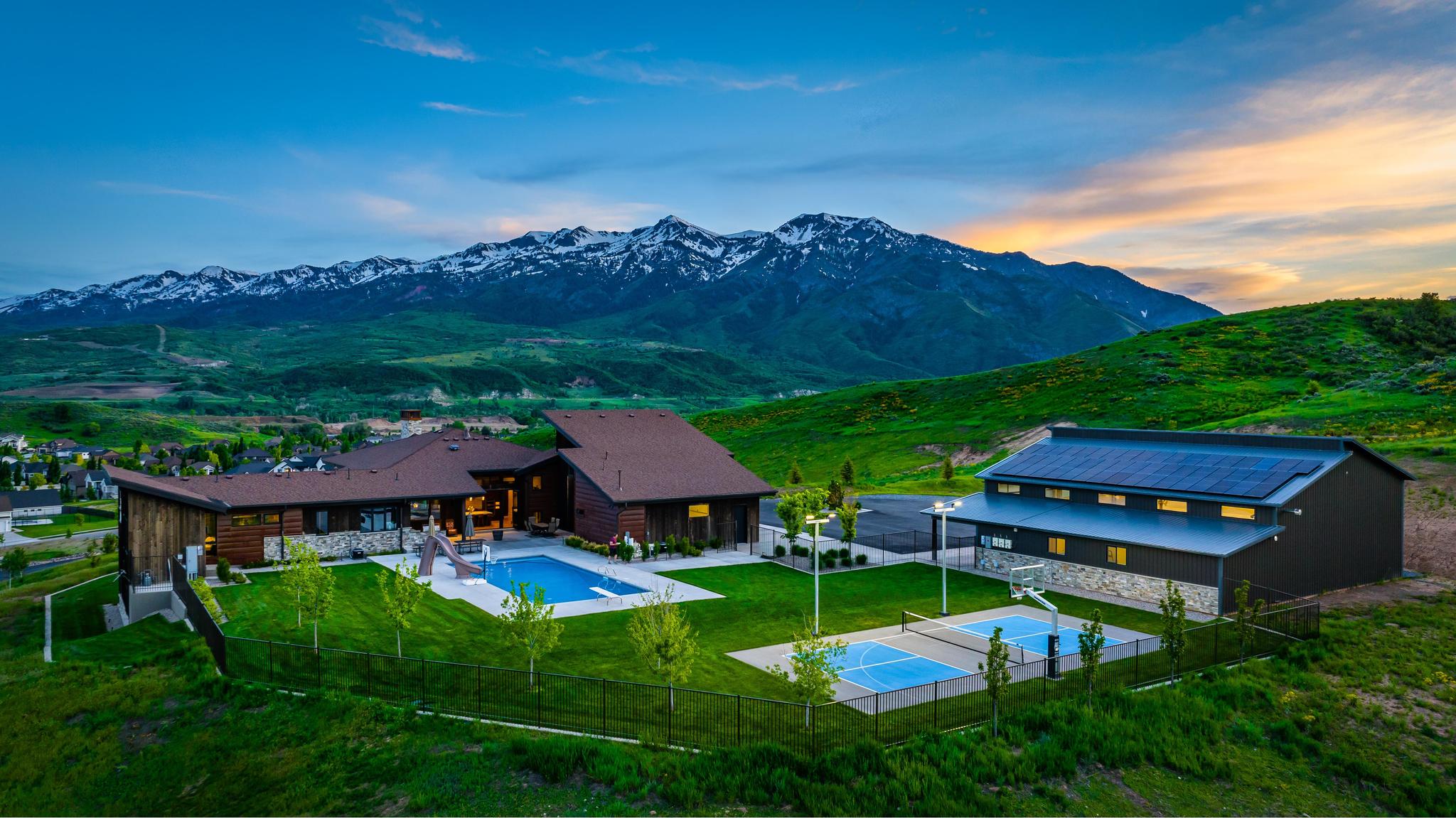 Contemporary residence featuring a large swimming pool, two sports courts, and a separate auxiliary building with rooftop solar panels