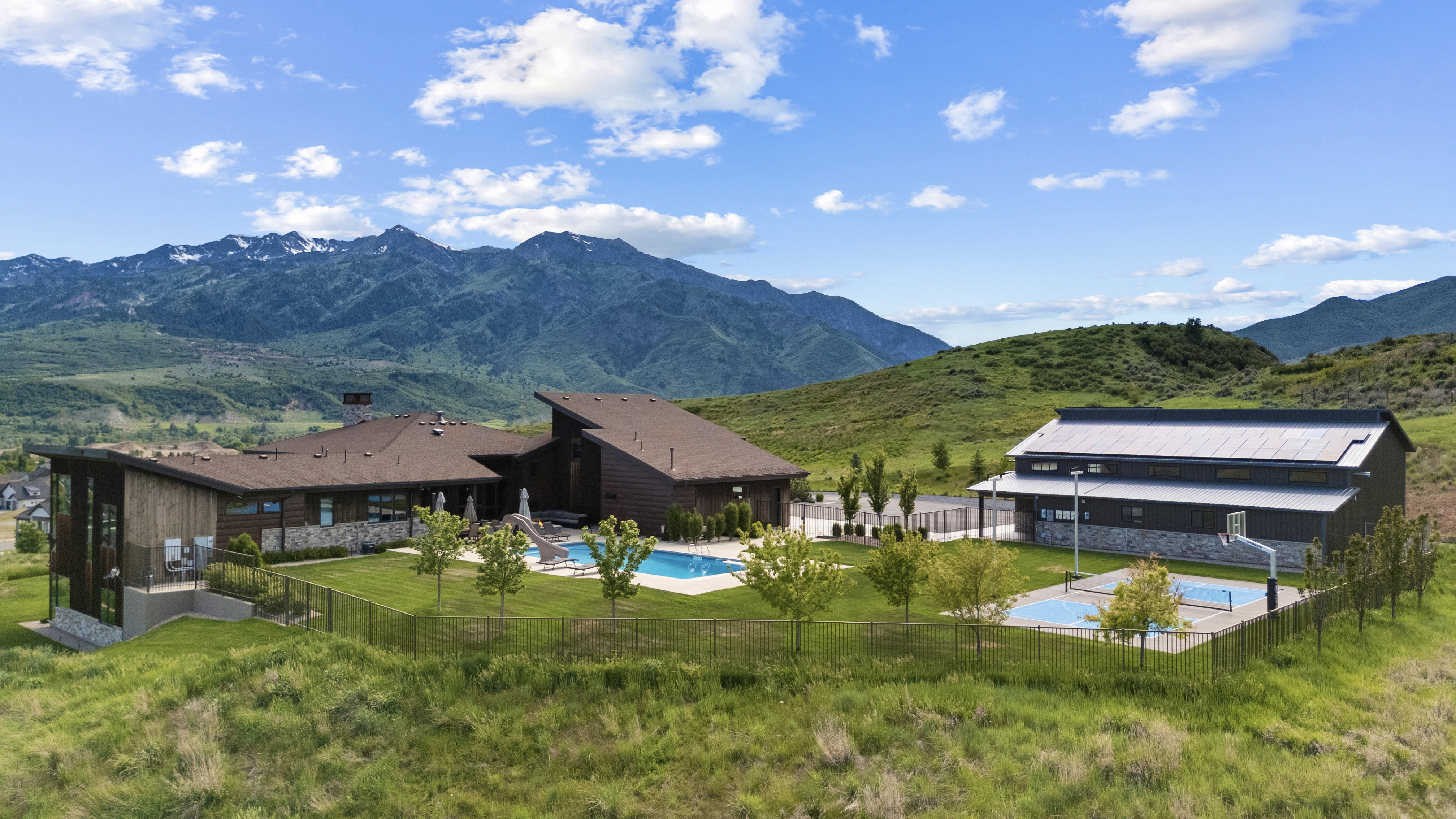 Architectural complex featuring a swimming pool, multiple sports courts, and mountain scenery