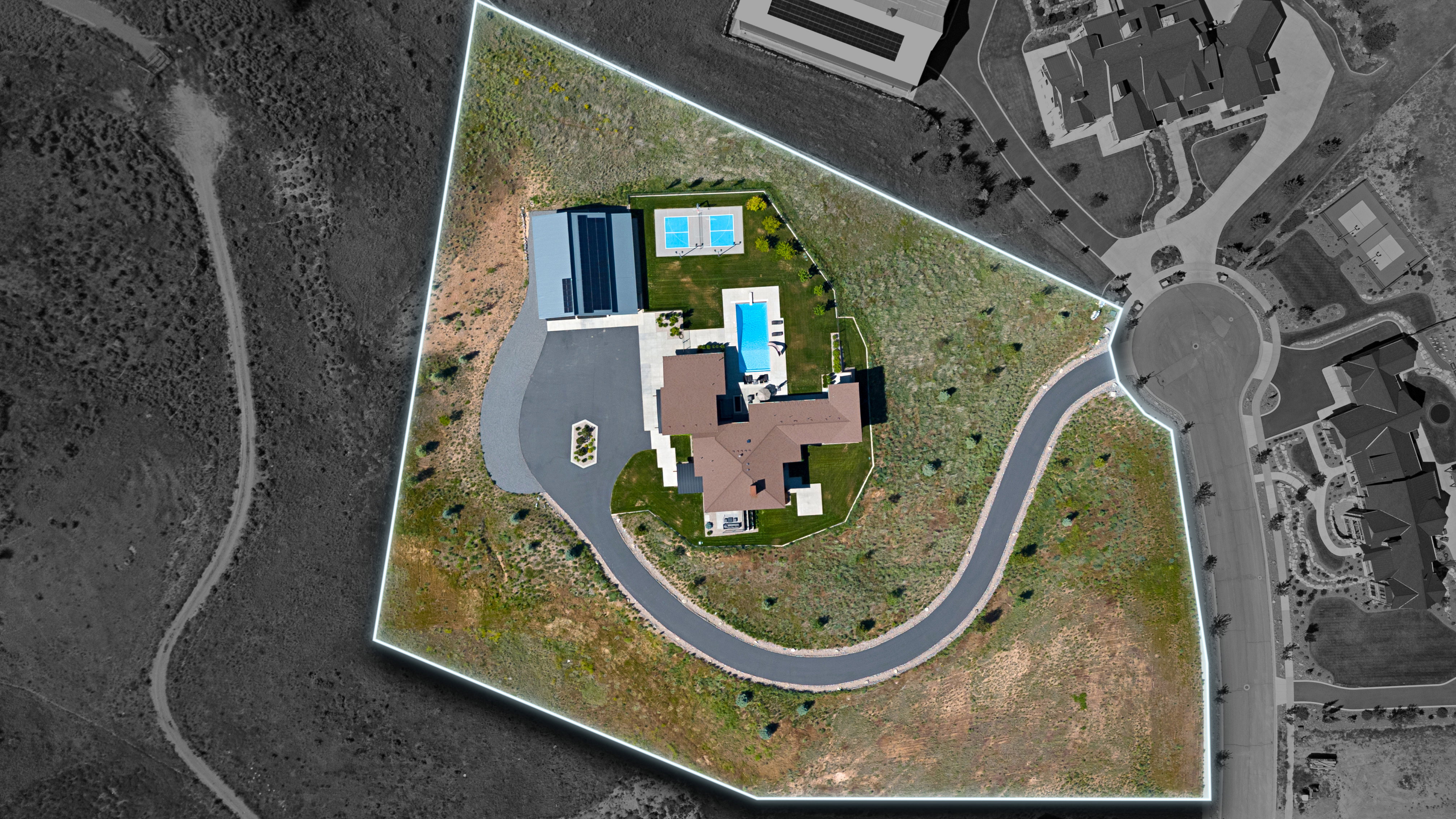 Expansive lot featuring a large residence, a private swimming pool, two sports courts, a winding driveway, and a separate structure with solar panels