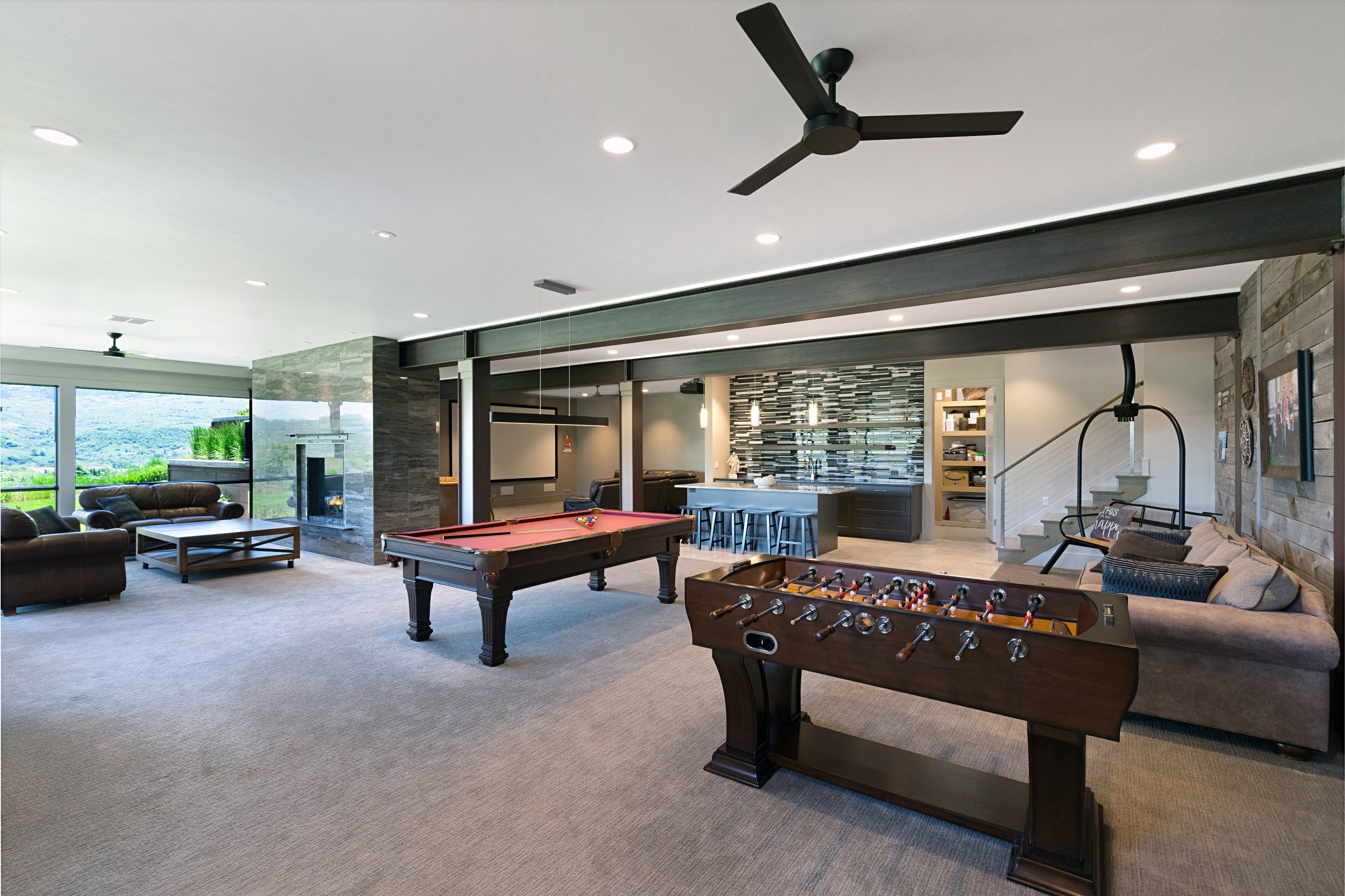 Spacious entertainment area featuring recessed lighting, a ceiling fan, and large picture windows