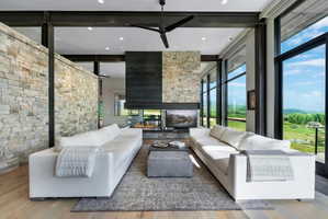 Living space with full-height stone accent wall, exposed structural beams, and wood-finish flooring