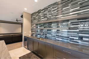 Wet bar with a mosaic tile accent wall, integrated beverage cooler, and undermount sink