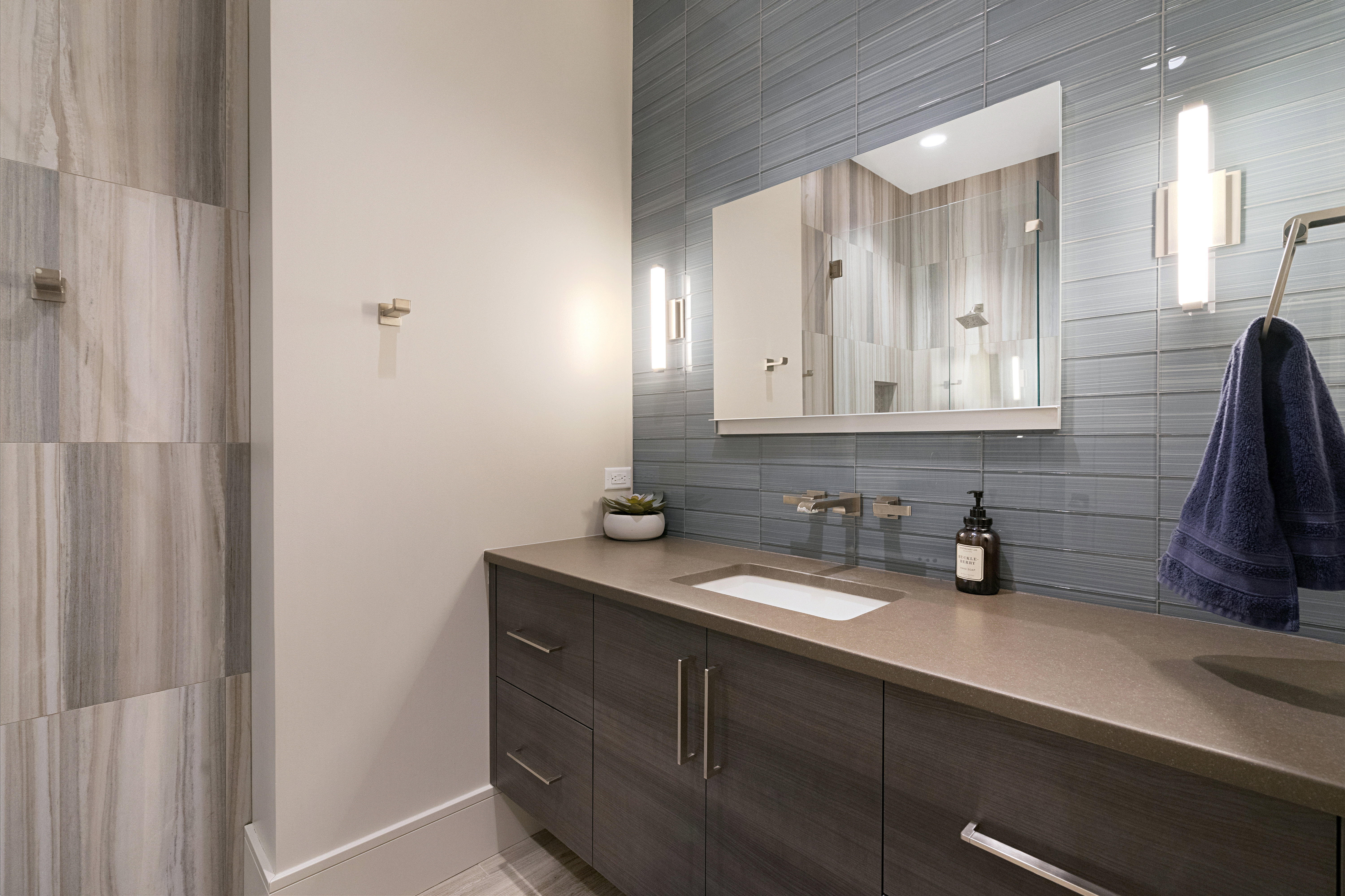 Bathroom vanity featuring an integrated rectangular sink with wall-mounted faucets, a large mirror, and two vertical sconces
