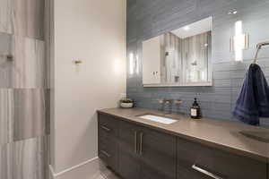 Bathroom vanity featuring an integrated rectangular sink with wall-mounted faucets, a large mirror, and two vertical sconces