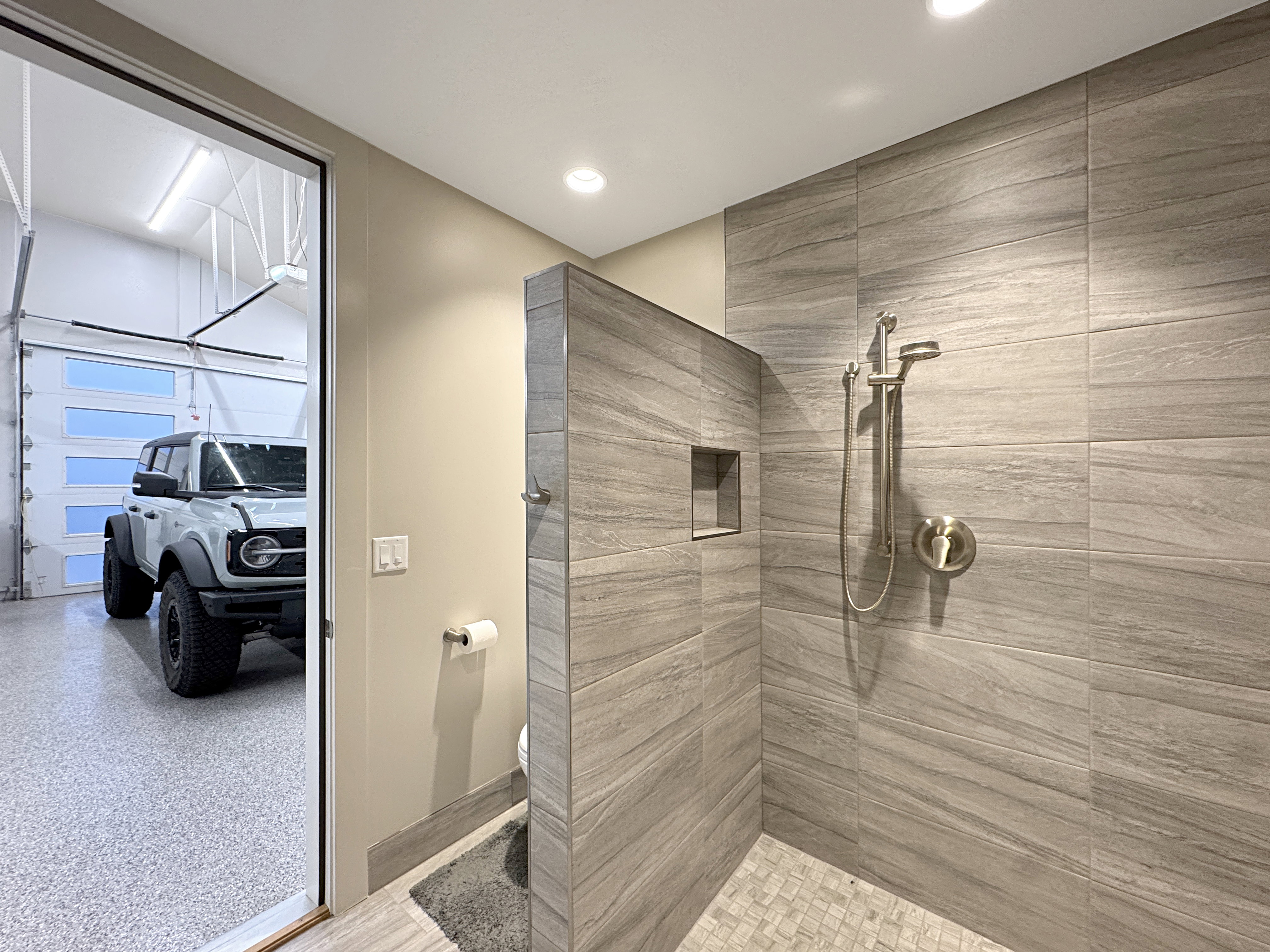 Walk-in shower with large format tile walls and a built-in niche