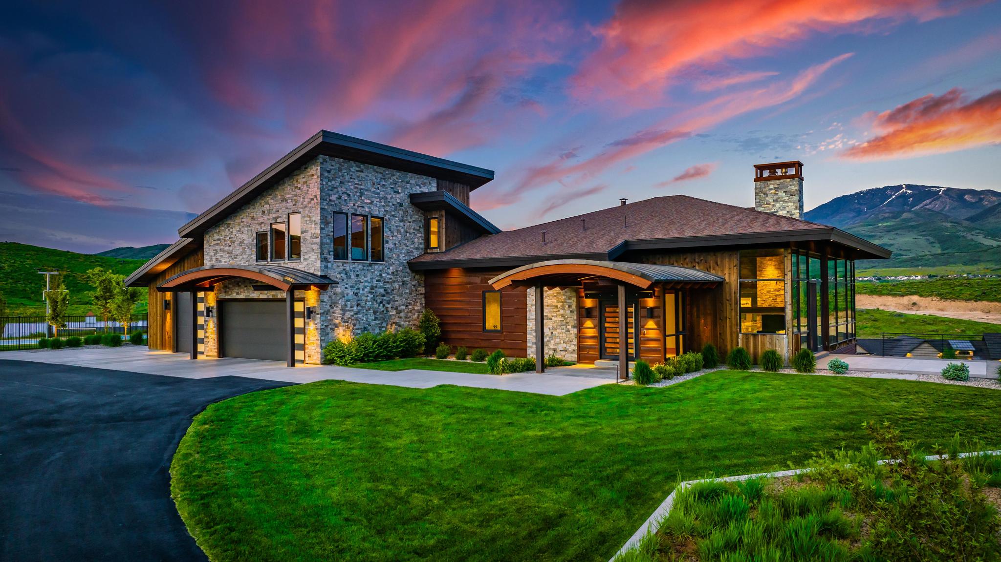 Modern contemporary exterior with stone and wood siding, a multi-paneled garage door, and a stone chimney