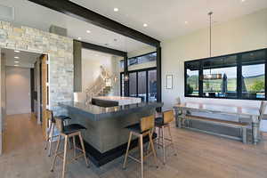 Open-concept living space featuring wood-finish flooring, a stone-clad accent wall, and a large breakfast bar with integrated seating