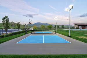 Multi-sport court featuring a basketball hoop, pickleball markings, and two tall athletic light poles