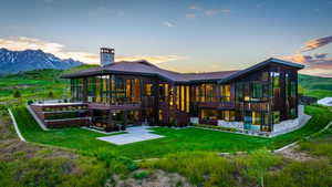 Modern architectural residence featuring extensive glass facades, a stone chimney, a multi-level wood exterior, and a flat roofline