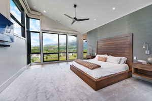 Spacious room featuring floor-to-ceiling windows, vaulted ceilings, light-toned carpeting, and a dark wood headboard with matching side tables