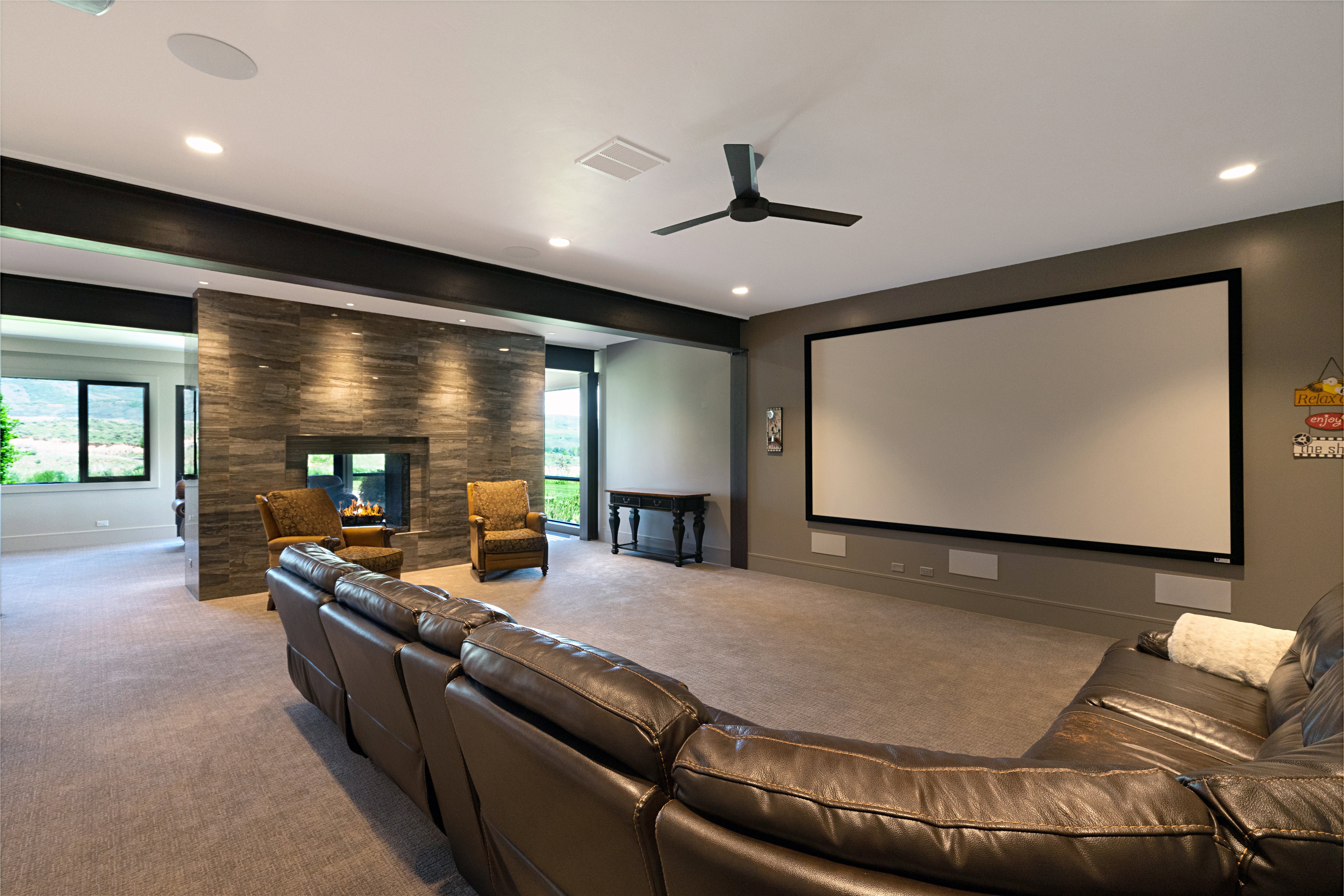Media room featuring a large projection screen, recessed lighting, and a modern ceiling fan