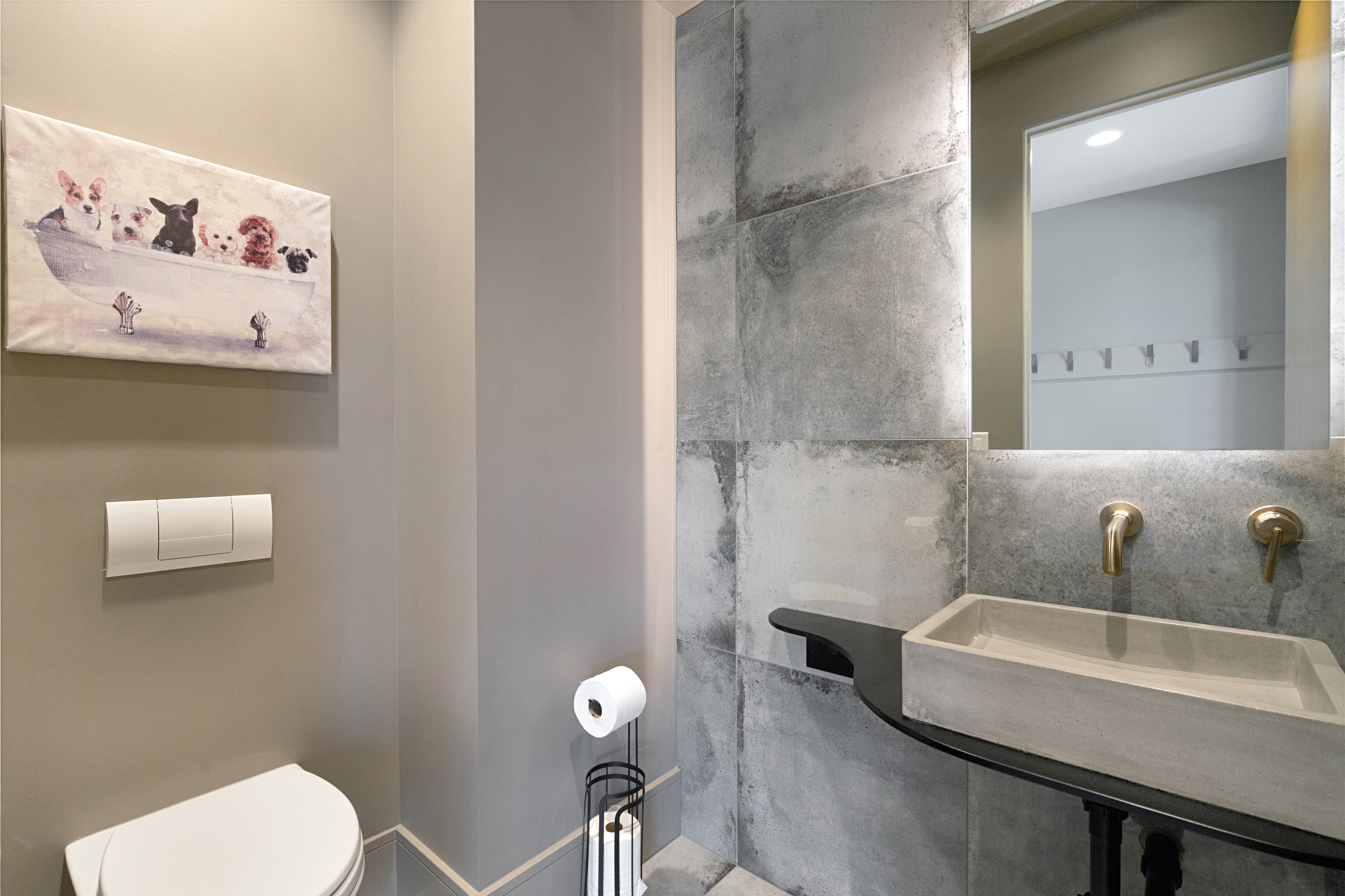 Bathroom featuring a wall-mounted toilet with flush plate, gray painted walls, and large format concrete-look wall tiling