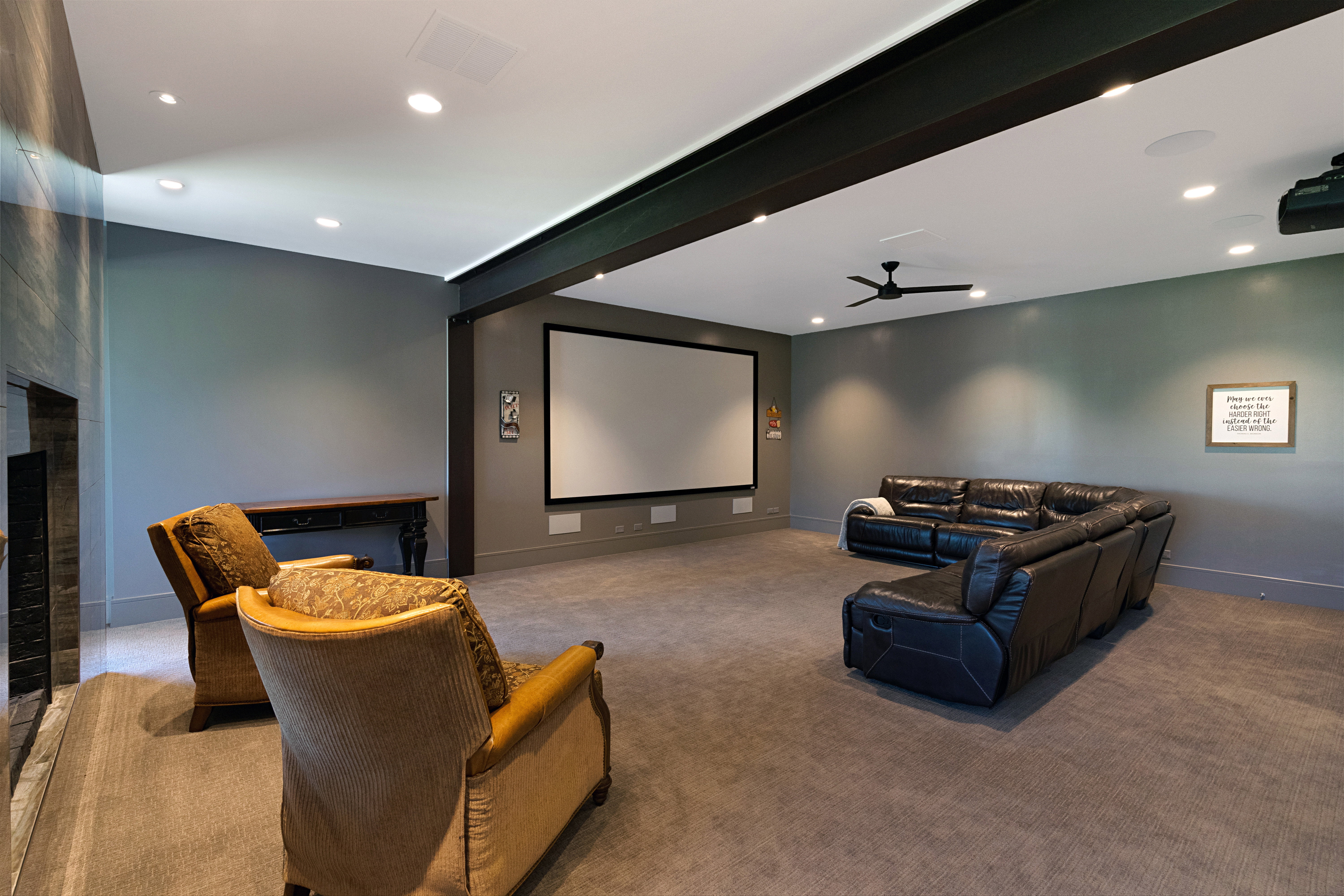 Spacious media room featuring a large projector screen, recessed lighting, ceiling fan, and carpeted flooring