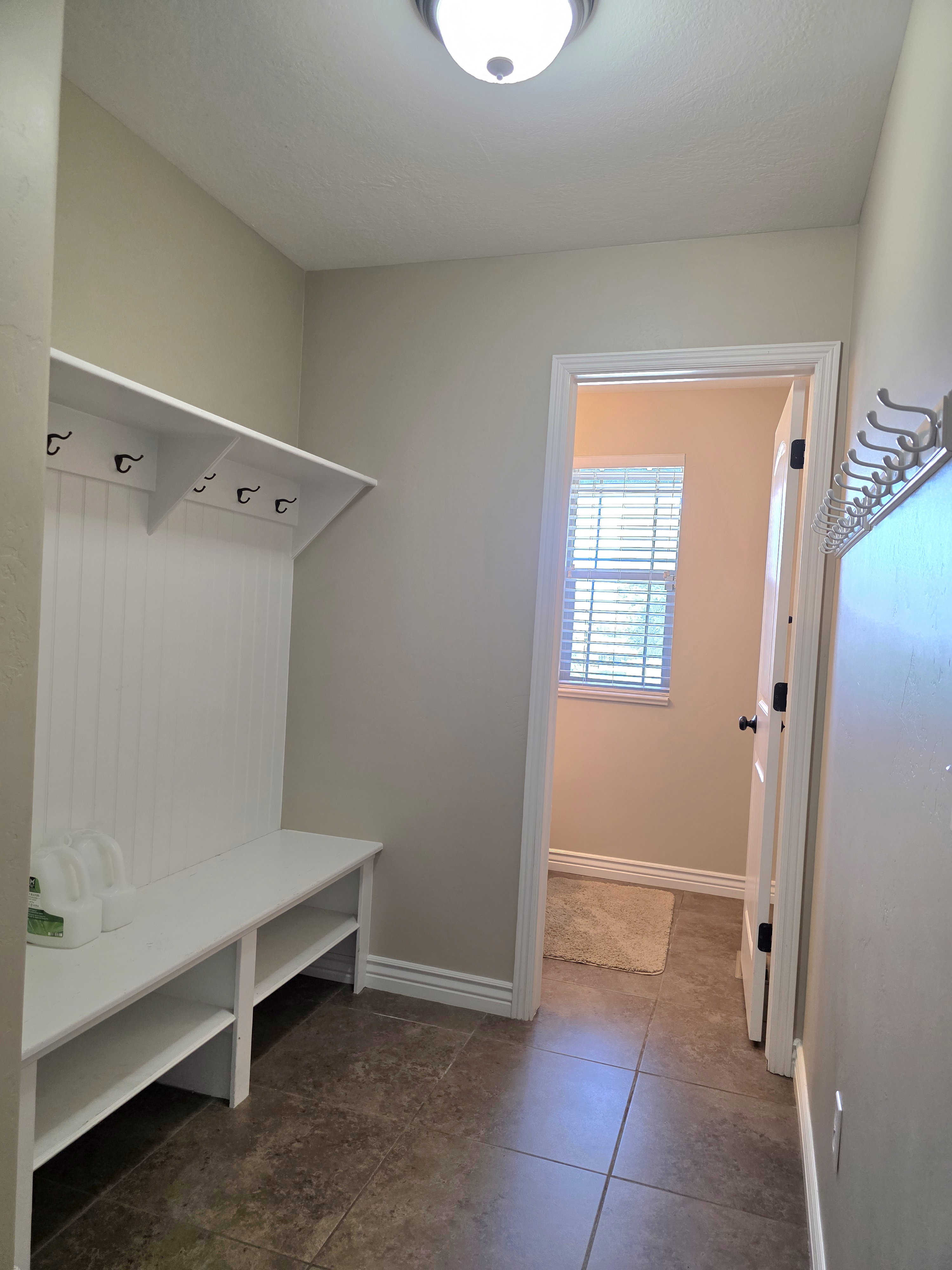 Entryway mudroom featuring a built-in bench with storage, beadboard paneling, and multiple coat hooks