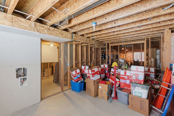 Unfinished basement offering exposed wood framing, visible ceiling joists, concrete flooring, and partial drywall installation