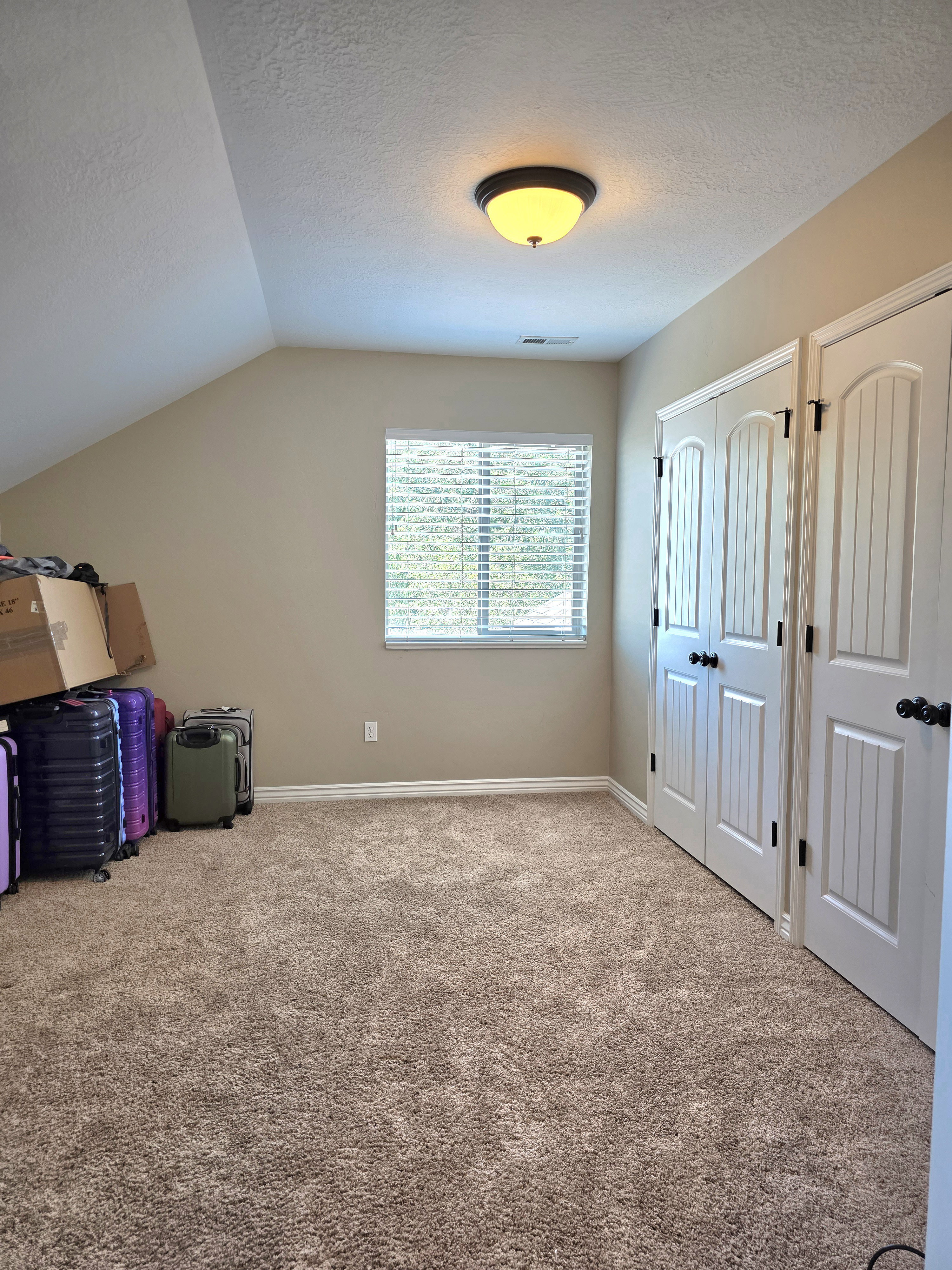 Carpeted room featuring a window with horizontal blinds, sloped ceiling, recessed lighting, and two bifold closet doors