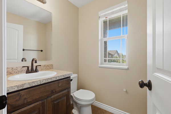 Bathroom featuring a single vanity with a stone-look countertop, a white oval sink, and a bronze-finish faucet