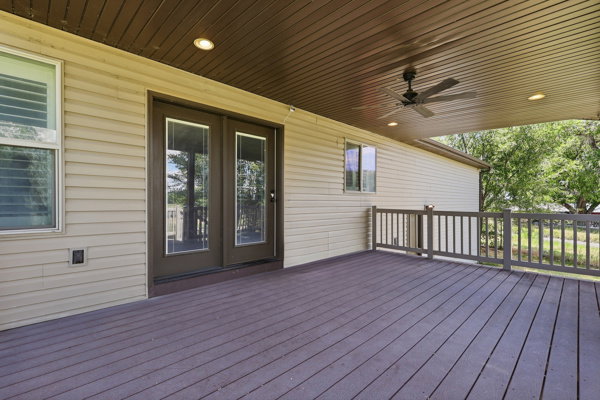 Covered outdoor deck featuring composite decking, a ceiling fan, recessed lighting, and a railing system
