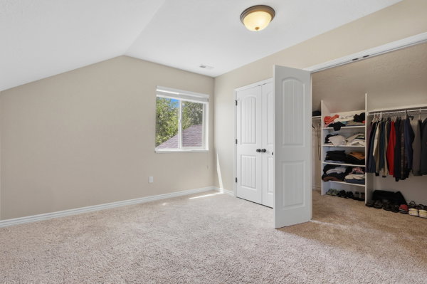 Carpeted room featuring a sloped ceiling and a double-hung window