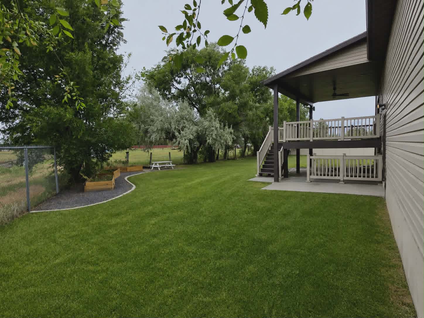 Spacious backyard featuring a multi-level deck, a covered patio, and a manicured lawn