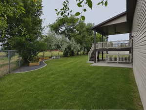 Spacious backyard featuring a multi-level deck, a covered patio, and a manicured lawn