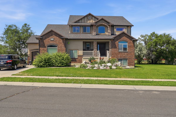 Two-story residence featuring a brick and stucco exterior, arched windows, and a covered porch with white railings
