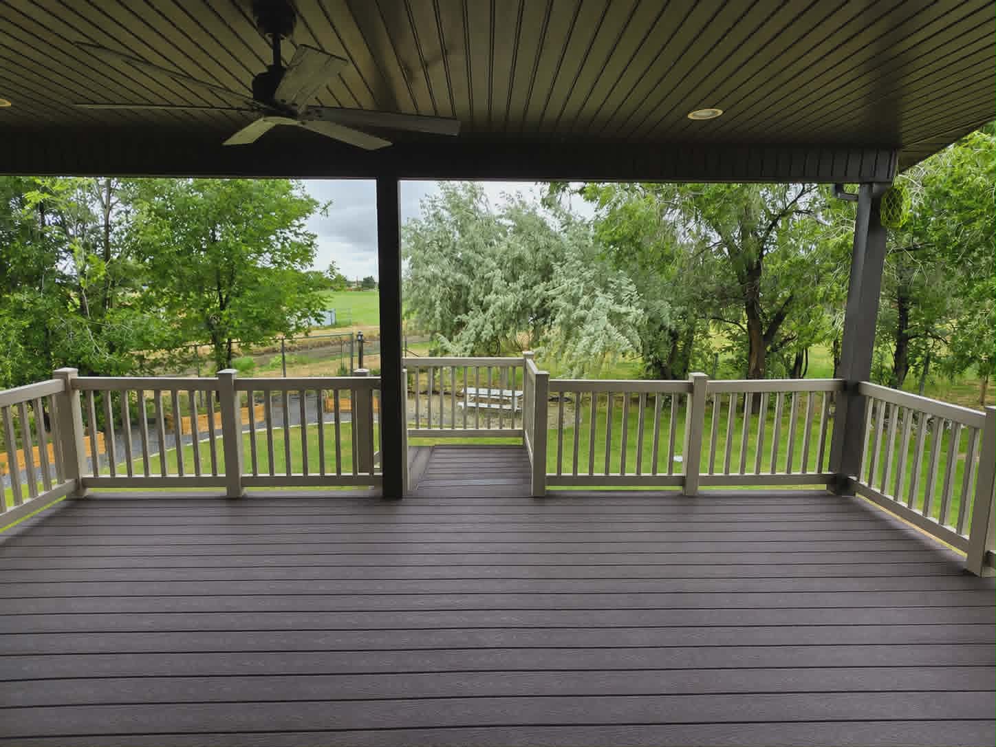 Covered deck featuring composite decking, painted wood railings, and a wood-paneled ceiling with recessed lighting and a ceiling fan