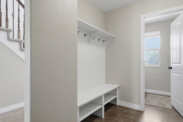 Entryway featuring a built-in bench with storage, coat hooks, and durable tile flooring