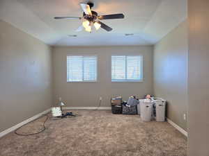 Spacious room featuring a tray ceiling with a ceiling fan, two windows with blinds, and neutral-toned wall-to-wall carpeting