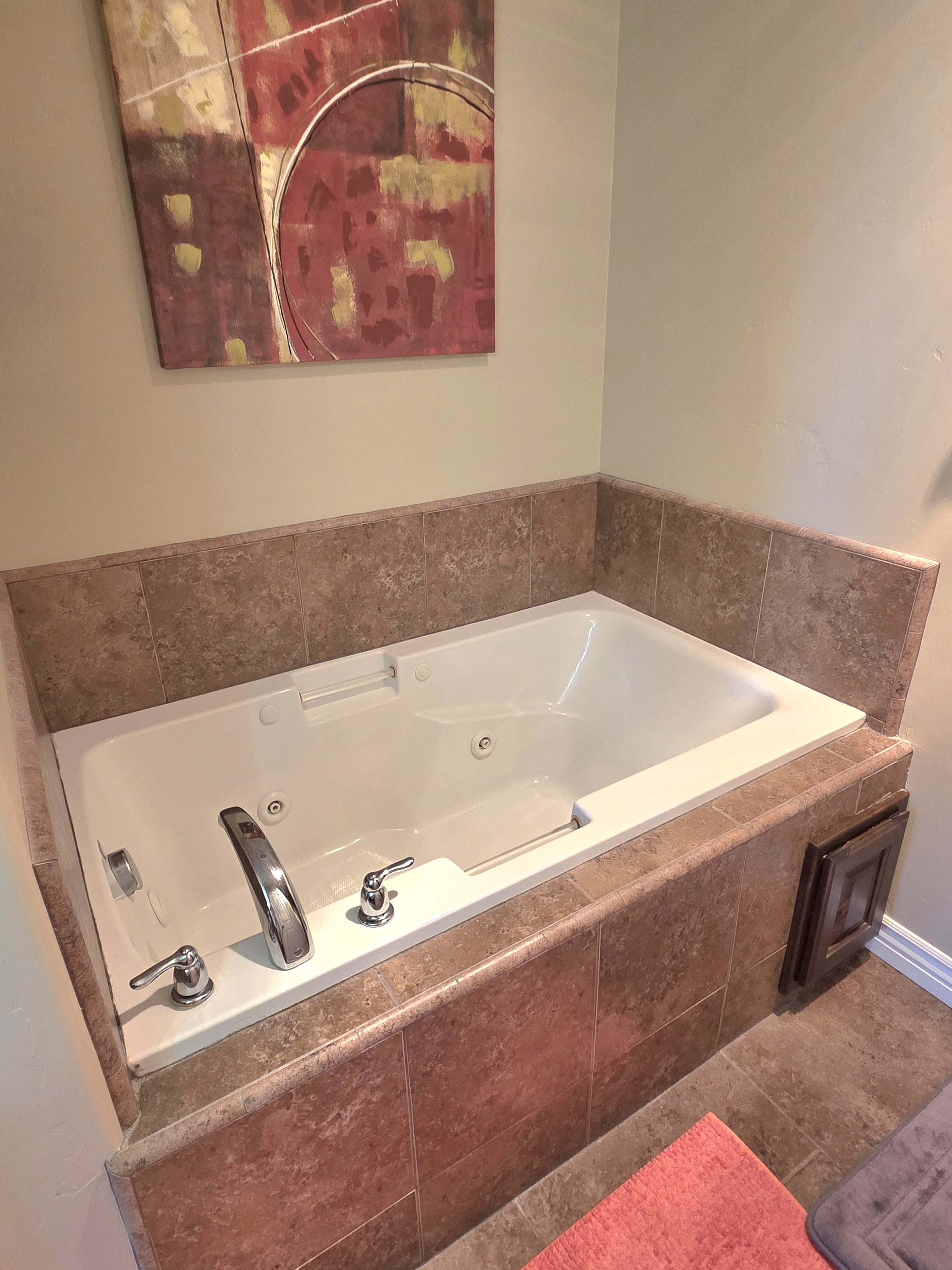 Soaking tub with jetted features, surrounded by ceramic tile, and chrome fixtures