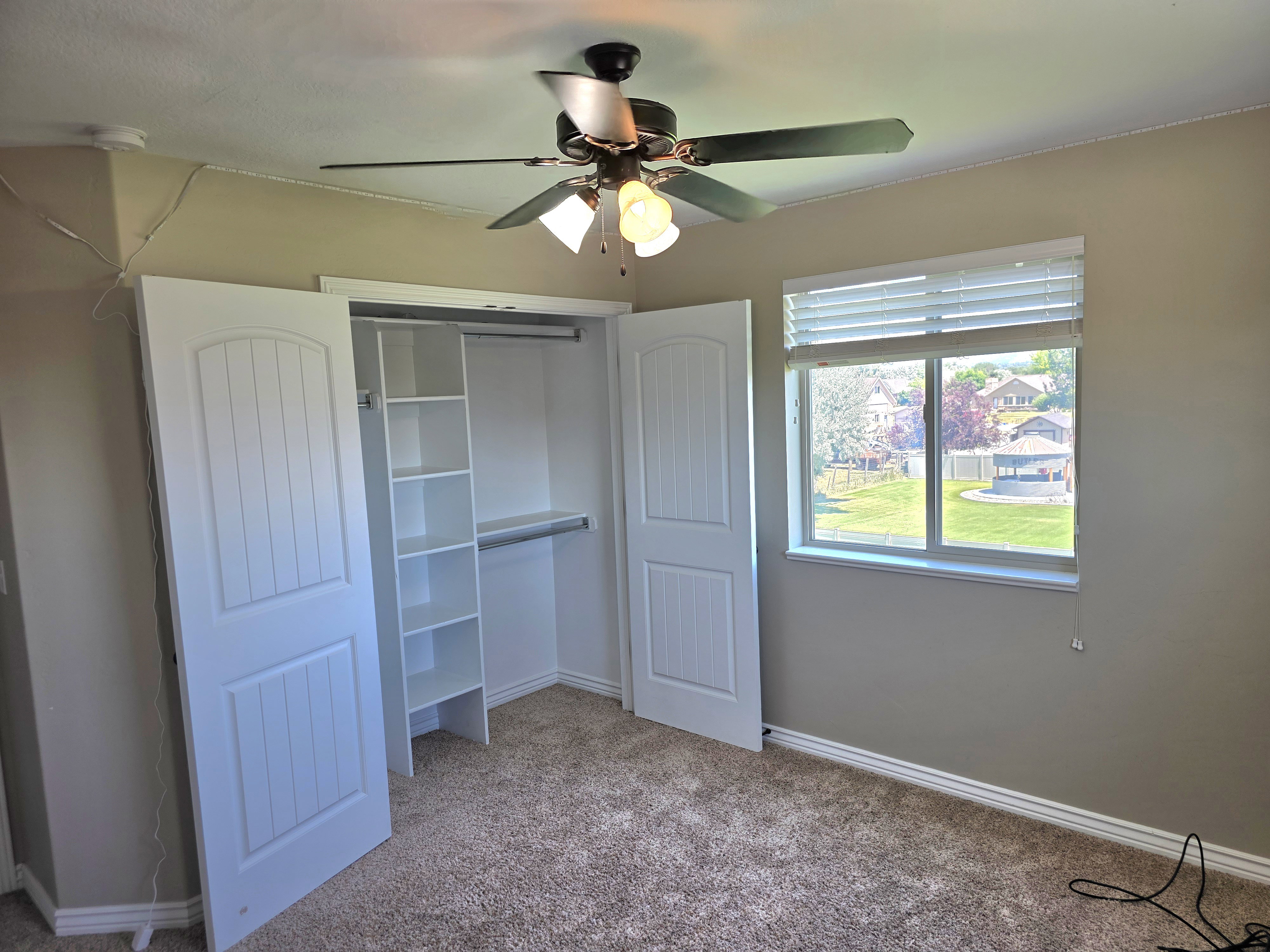 Carpeted room featuring a built-in closet with shelving and hanging rods